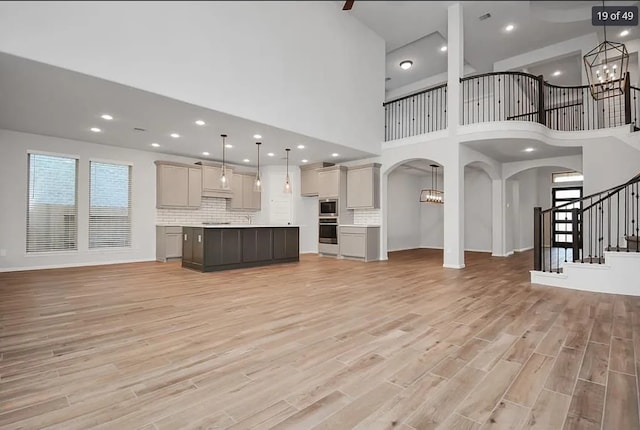 unfurnished living room featuring a chandelier, light hardwood / wood-style flooring, and a wealth of natural light