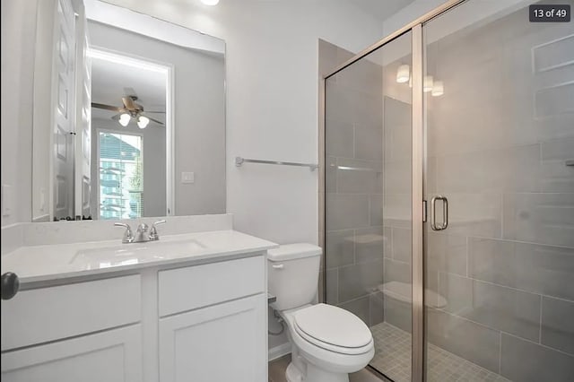 bathroom featuring ceiling fan, vanity, toilet, and a shower with shower door