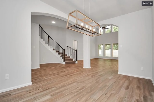 interior space with wood-type flooring, a towering ceiling, and an inviting chandelier