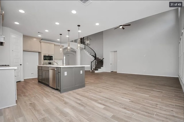 kitchen with light wood-type flooring, dishwasher, an island with sink, pendant lighting, and ceiling fan