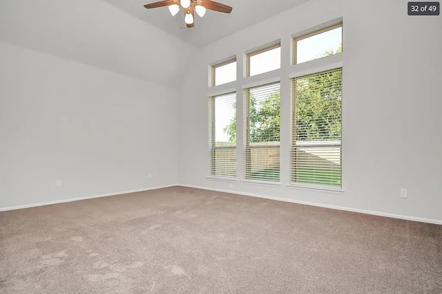 carpeted spare room featuring ceiling fan and a high ceiling