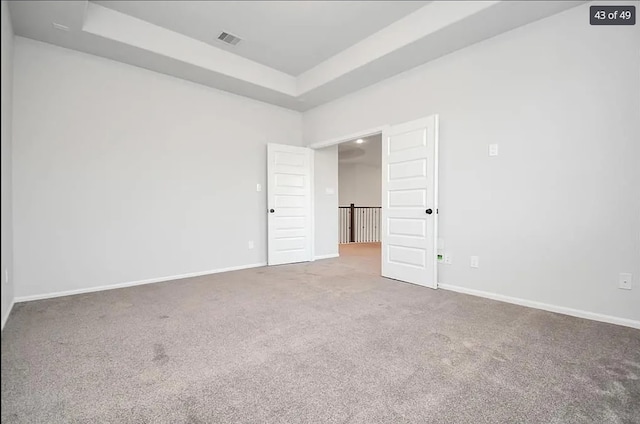 empty room with a tray ceiling and carpet