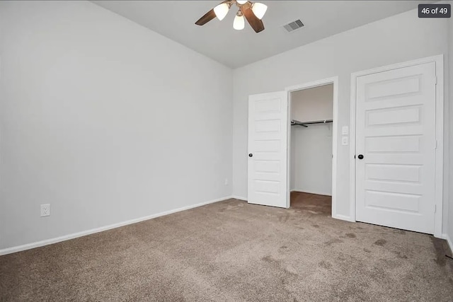 unfurnished bedroom featuring ceiling fan, a spacious closet, carpet floors, and a closet