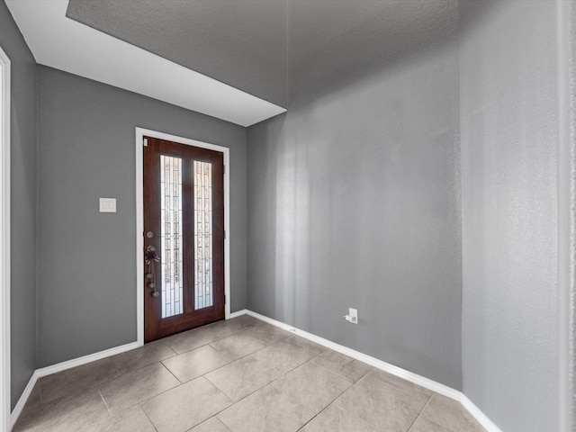 foyer entrance with light tile patterned floors and baseboards