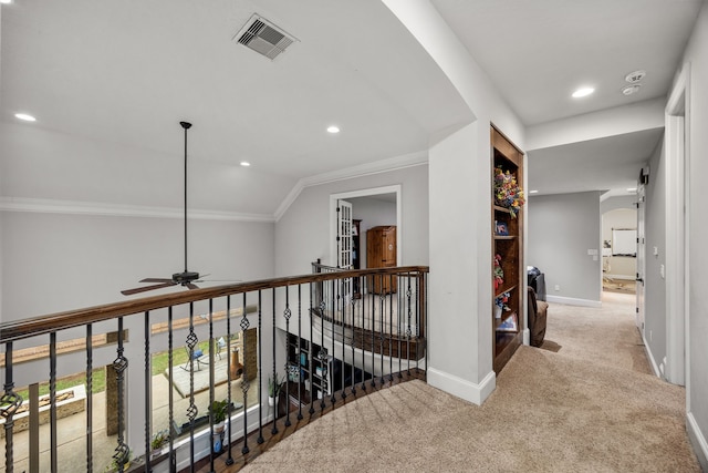 corridor with ornamental molding, vaulted ceiling, and carpet flooring