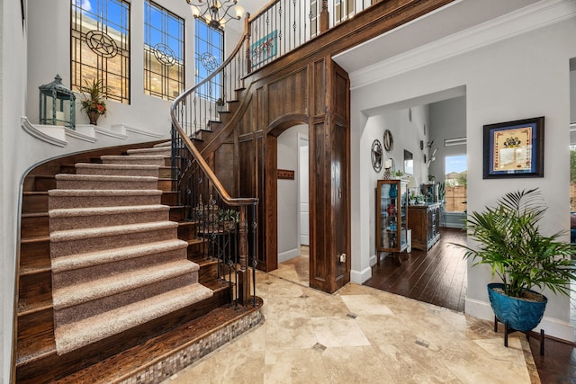 staircase featuring a notable chandelier, a towering ceiling, and ornamental molding