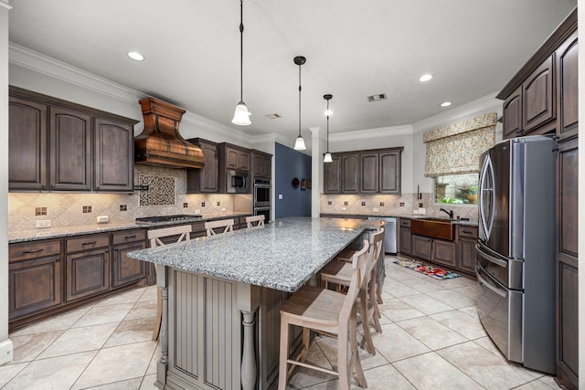 kitchen featuring dark brown cabinetry, appliances with stainless steel finishes, custom range hood, and a kitchen island