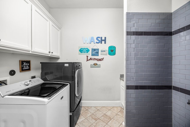 clothes washing area featuring cabinets, washing machine and dryer, and light tile patterned floors