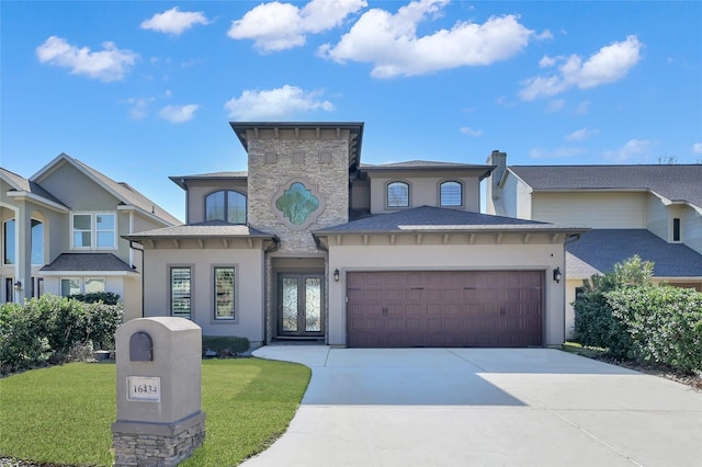 view of front of house featuring a garage, concrete driveway, a front lawn, and stucco siding