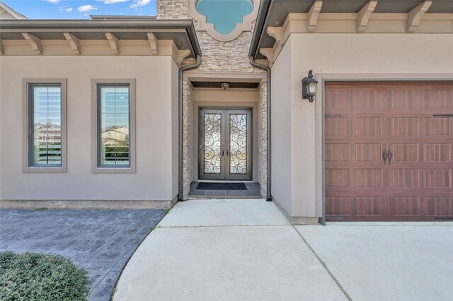 property entrance with a garage, stone siding, a chimney, and stucco siding