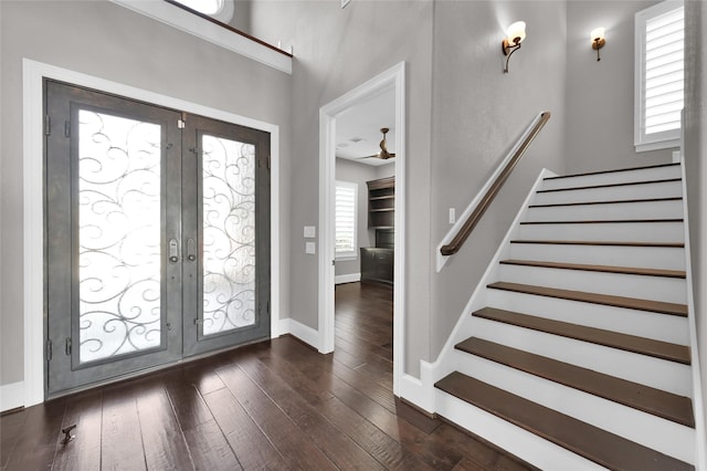 foyer entrance with dark wood-style floors, french doors, baseboards, and stairs