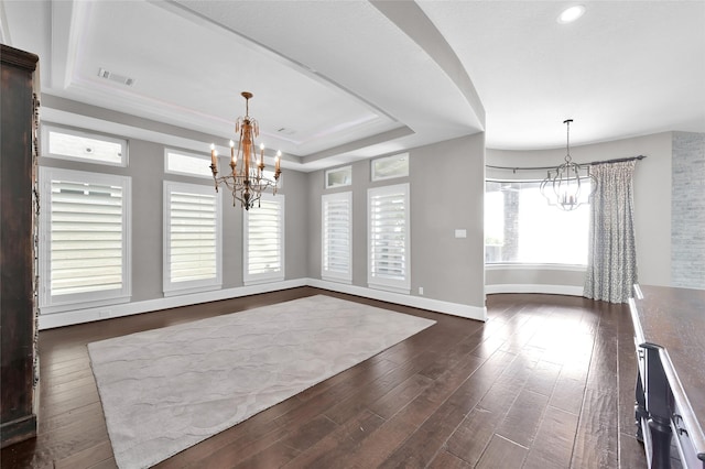 unfurnished dining area with dark wood-type flooring, a tray ceiling, visible vents, and an inviting chandelier