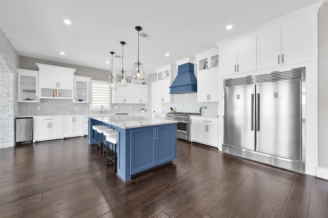 kitchen with a center island, custom exhaust hood, open shelves, high quality appliances, and blue cabinets