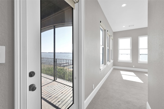 entryway featuring a water view, carpet, baseboards, and a textured wall