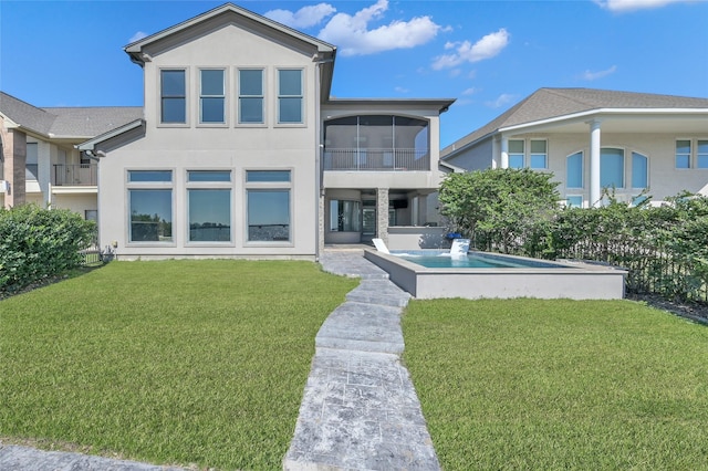 rear view of property with an outdoor pool, a sunroom, a yard, and stucco siding