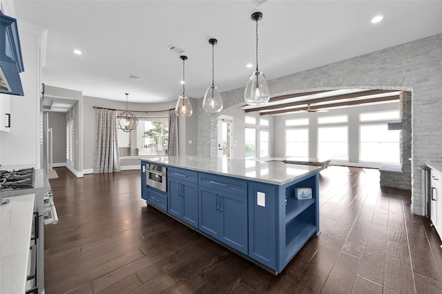 kitchen with stainless steel stove, ceiling fan with notable chandelier, blue cabinetry, open shelves, and dark wood finished floors