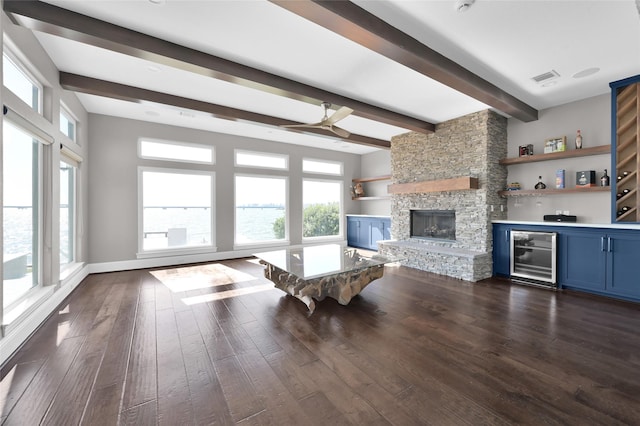 unfurnished living room with dark wood-type flooring, wine cooler, a stone fireplace, and a bar