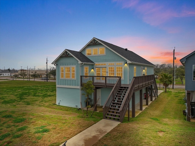 back of house featuring board and batten siding, a yard, stairway, and a deck