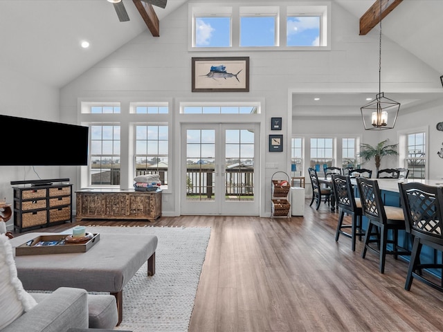 living room featuring beam ceiling, high vaulted ceiling, wood-type flooring, ceiling fan with notable chandelier, and french doors