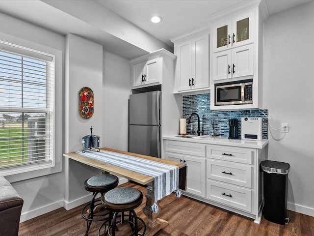 kitchen featuring dark wood-type flooring, sink, appliances with stainless steel finishes, white cabinets, and backsplash