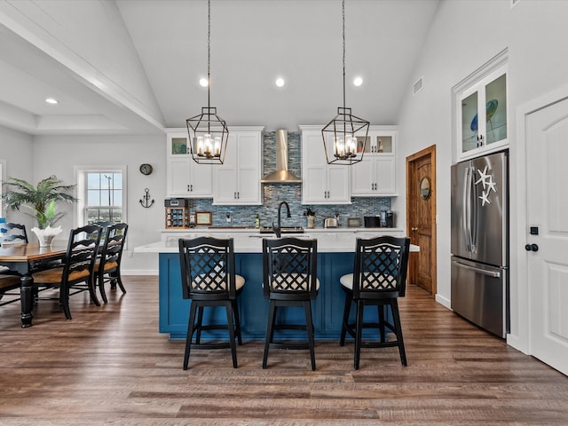 kitchen with stainless steel refrigerator, white cabinets, a kitchen island with sink, and pendant lighting