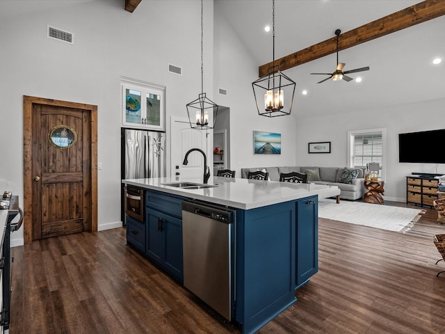 kitchen with blue cabinets, sink, hanging light fixtures, a center island with sink, and stainless steel appliances