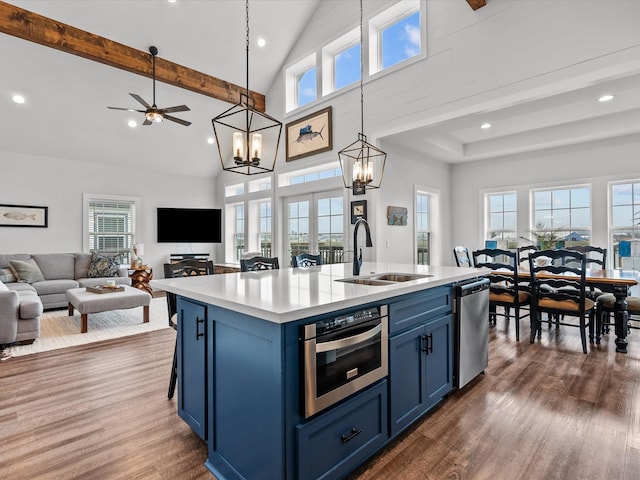 kitchen with sink, hanging light fixtures, stainless steel appliances, an island with sink, and blue cabinets