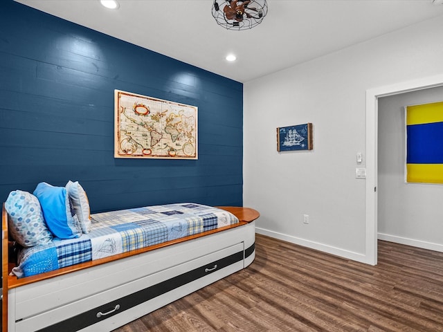 bedroom featuring hardwood / wood-style flooring and wooden walls