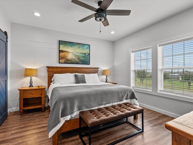 bedroom with ceiling fan, a barn door, and hardwood / wood-style floors