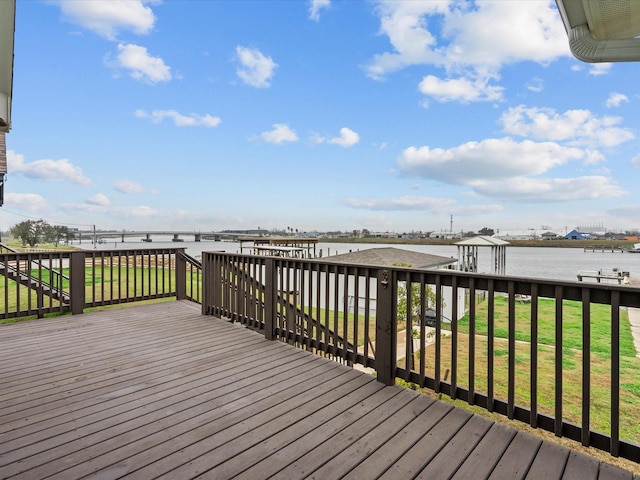 wooden terrace with a water view and a yard