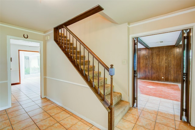 stairs featuring tile patterned flooring, ornamental molding, and wood walls