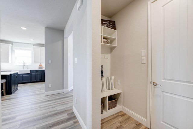 mudroom featuring light wood-type flooring, baseboards, a sink, and recessed lighting