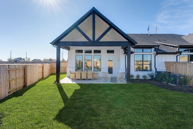 rear view of house featuring a patio area, central air condition unit, a shingled roof, a fenced backyard, and a yard