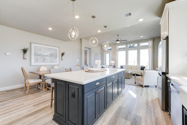 kitchen featuring a ceiling fan, light countertops, visible vents, and light wood-type flooring