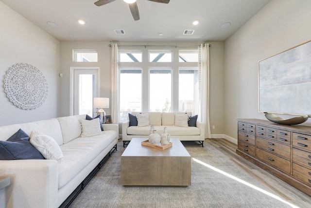 living area featuring baseboards, a ceiling fan, visible vents, and light wood-type flooring