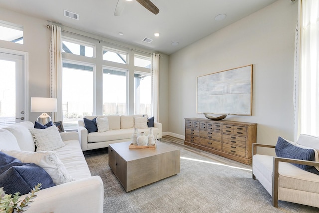living area featuring baseboards, a ceiling fan, and visible vents