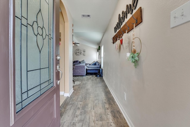 hallway with wood-type flooring and vaulted ceiling