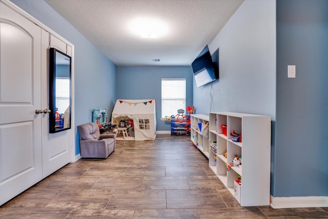 game room featuring wood-type flooring and a textured ceiling