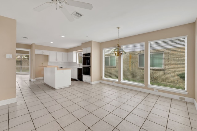 kitchen featuring decorative light fixtures, white cabinetry, a center island, light tile patterned floors, and plenty of natural light