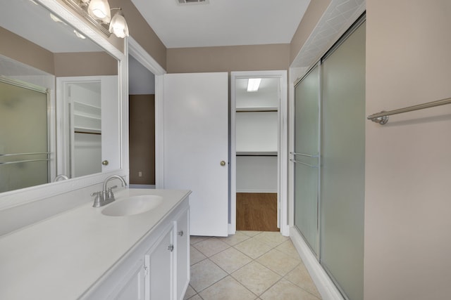 bathroom featuring tile patterned floors, a shower with door, and vanity