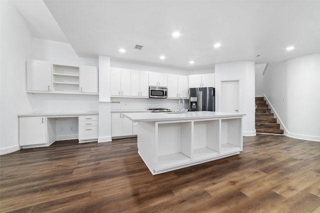 kitchen featuring white cabinetry, dark hardwood / wood-style flooring, an island with sink, stainless steel appliances, and backsplash