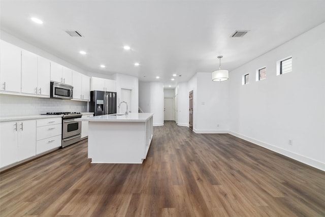 kitchen featuring decorative light fixtures, tasteful backsplash, white cabinetry, an island with sink, and stainless steel appliances