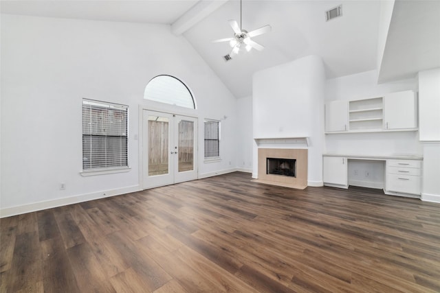 unfurnished living room featuring a tile fireplace, dark wood-type flooring, ceiling fan, and beam ceiling