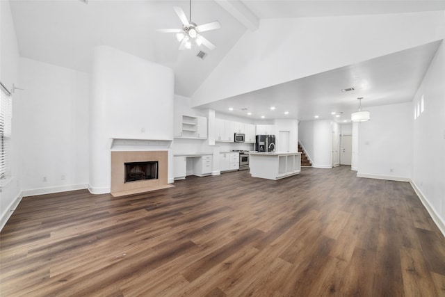 unfurnished living room with high vaulted ceiling, dark hardwood / wood-style flooring, beamed ceiling, ceiling fan, and a tiled fireplace