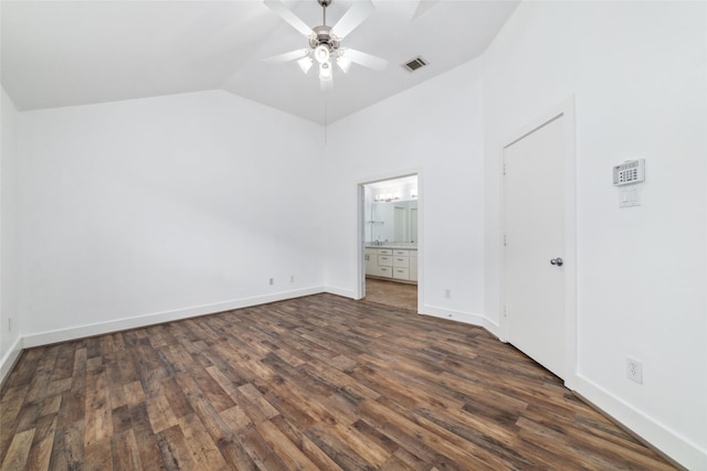 unfurnished bedroom with lofted ceiling, connected bathroom, dark wood-type flooring, and ceiling fan