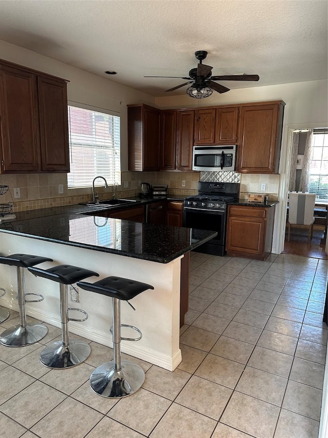 1723 Park Ridge Dr, Katy, TX 77450 - kitchen with range with gas stovetop, stainless steel microwave, a sink, a peninsula, and a breakfast bar
