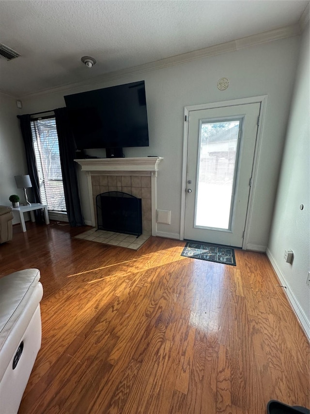 1723 Park Ridge Dr, Katy, TX 77450 - unfurnished living room with wood finished floors, a tile fireplace, crown molding, and a textured ceiling