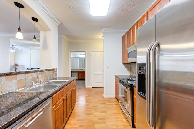 kitchen featuring crown molding, appliances with stainless steel finishes, sink, and decorative light fixtures