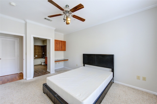 bedroom featuring built in desk, connected bathroom, carpet flooring, ornamental molding, and ceiling fan