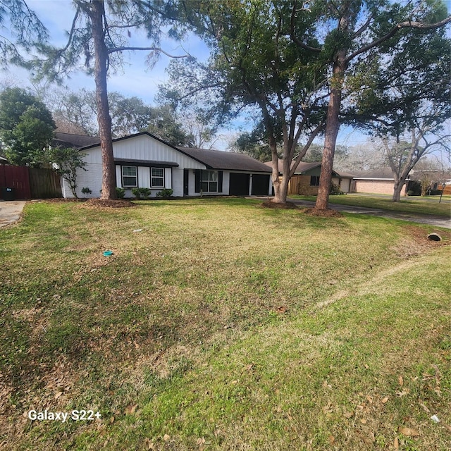 single story home featuring board and batten siding, a front yard, and fence